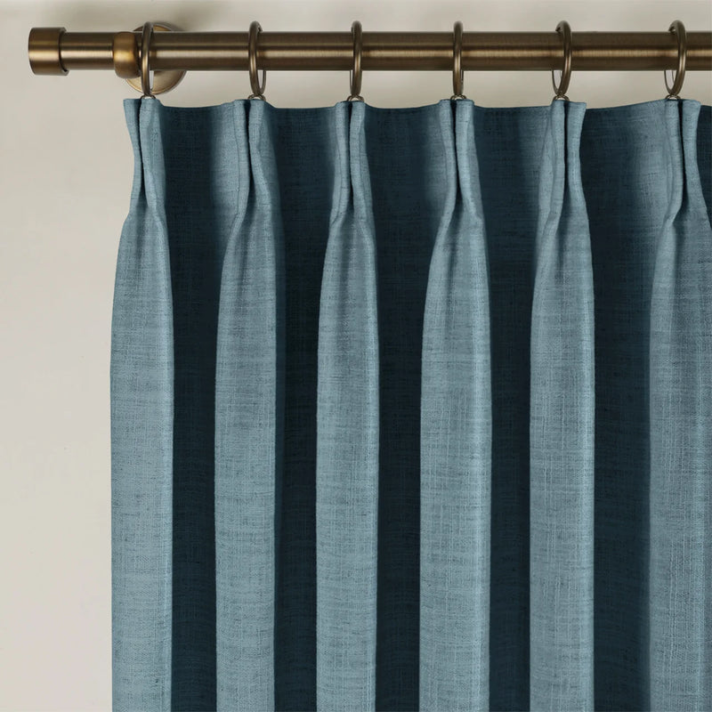 Aegean Blue Liz linen curtains viewed at an angle in a softly styled room with natural daylight