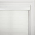 White fabric zebra roller Blind with alternating sheer and opaque horizontal strips hanging inside a white window frame with decorative molding and a control cord on the right
