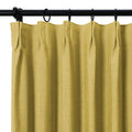 Chartreuse green woven fabric curtain with a pinch pleat top hanging from a black rod with dark rings showcasing soft vertical folds