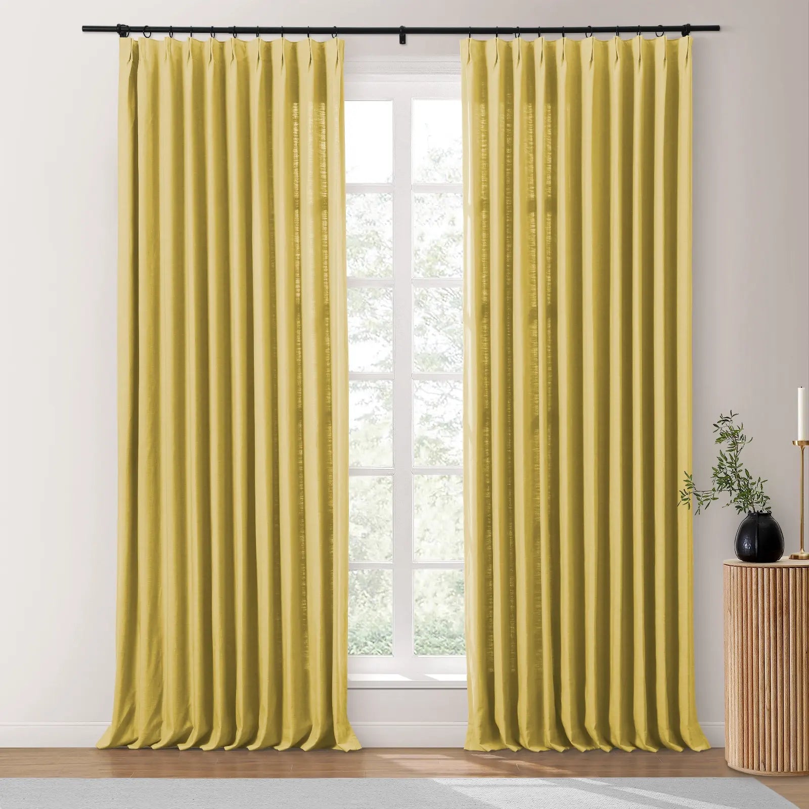 Pair of chartreuse textured linen curtains hanging on a black rod, framing a bright window revealing outdoor greenery, beside a fluted wood side table with a black vase and white candle
