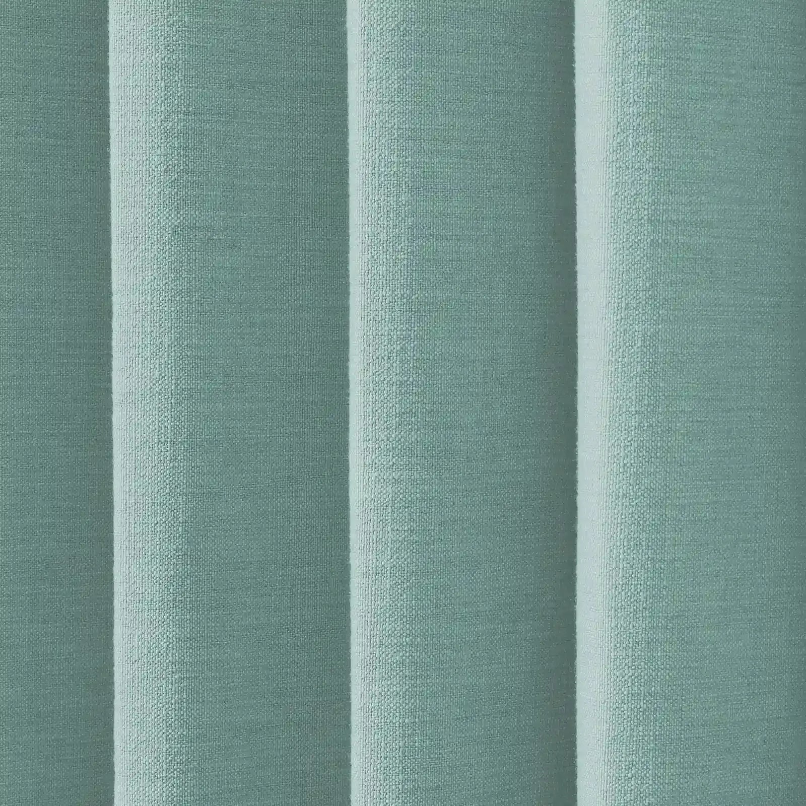 Textured fabric displaying vertical folds in a pale teal color with a woven bouclé texture and subtle light and shadow