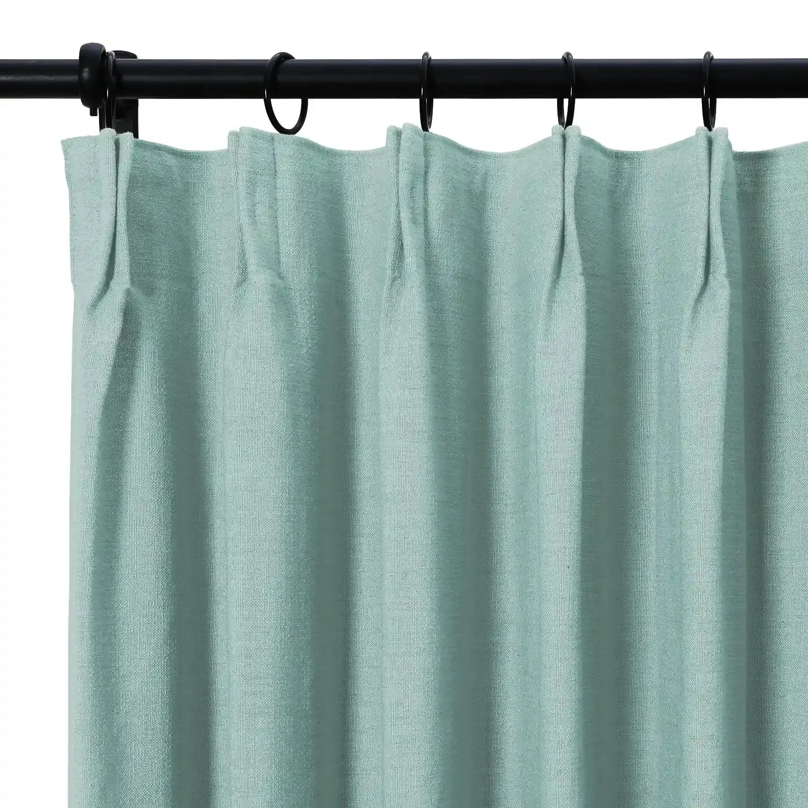 Light teal woven curtain with a pleated header hanging from black rings on a black rod