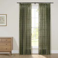 A pair of green botanical print pleated curtains framing a sunlit window in a neutral room interior featuring a light wooden dresser and framed botanical art