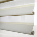 Layered sheer and opaque fabric window Blinds in a modern interior featuring pale gray and light yellow striped patterns with a textured surface and neatly rolled bottom edge