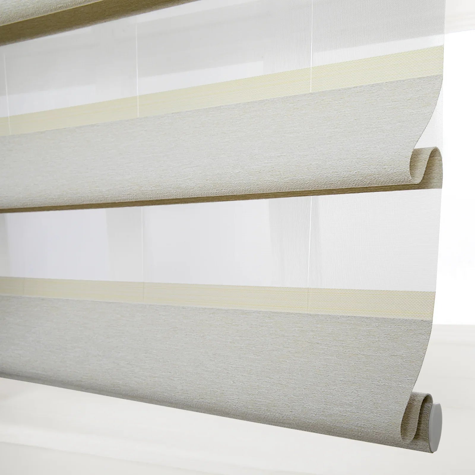 Layered sheer and opaque fabric window Blinds in a modern interior featuring pale gray and light yellow striped patterns with a textured surface and neatly rolled bottom edge
