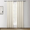 Photograph of cream-colored blackout curtains with black grommet tops on a black rod in a modern room featuring an abstract wall painting