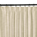 Photograph of a light beige textured linen-look pinch pleat curtain hanging from a black curtain rod with rings
