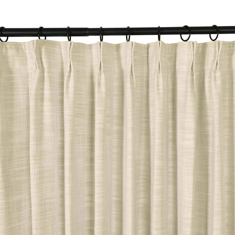 Photograph of a light beige textured linen-look pinch pleat curtain hanging from a black curtain rod with rings