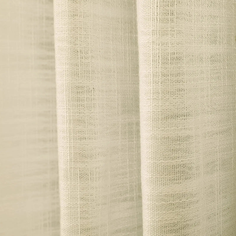 Photograph of a cream-colored linen curtain with a loose weave and soft vertical folds