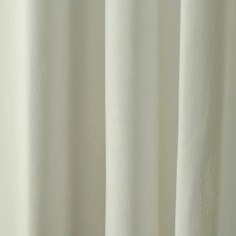 Photograph of a creamy off-white textured fabric curtain featuring soft vertical folds and subtle light and shadow interplay