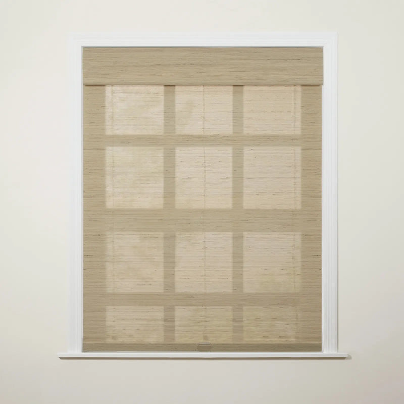 Photograph of a window in an interior room featuring a light beige woven Roman blind with visible horizontal folds and faint grid-like shadows cast upon it from behind, framed by white molding