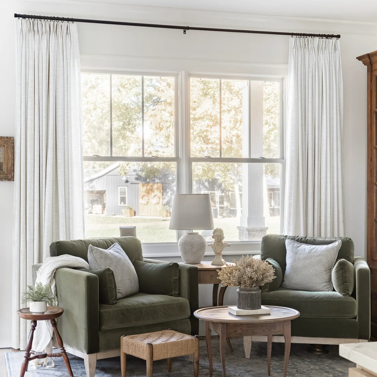 Beige White Liz Linen Pleated Curtains framing a green sofa beneath a wide sunlit window
