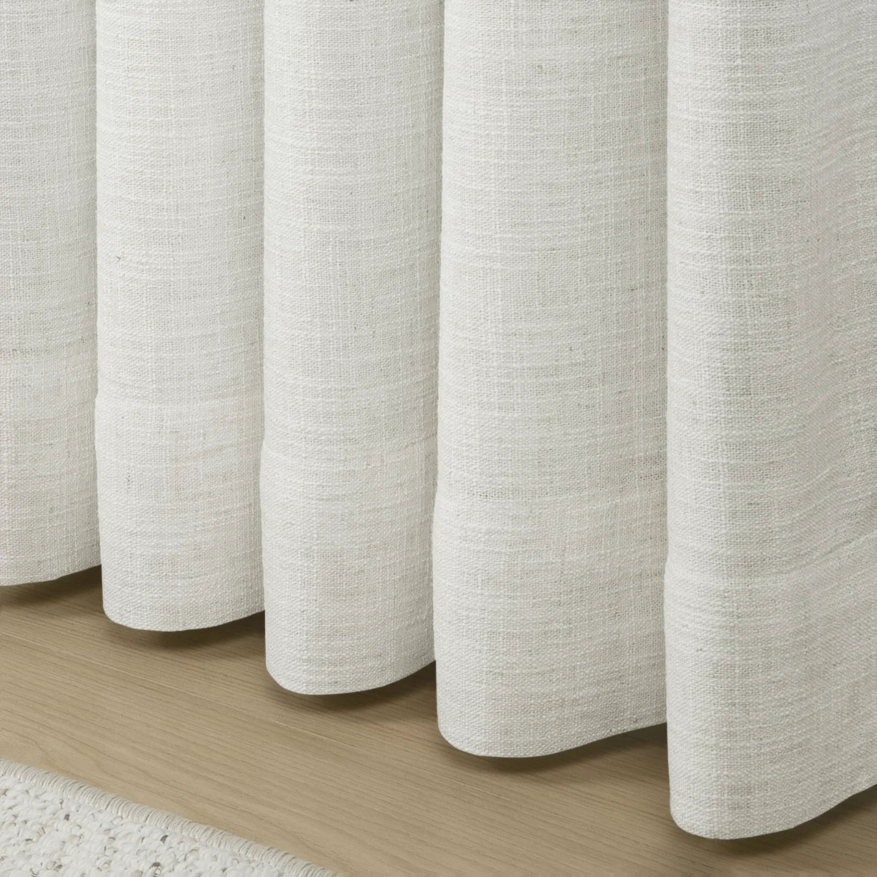 Beige White Liz Linen Pleated Curtains rounded curtain hems above a pale wood floor