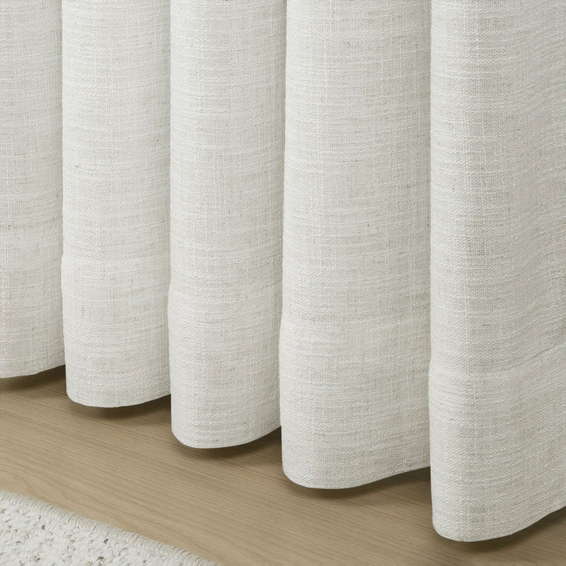 Beige White Liz Linen Pleated Curtains rounded curtain hems above a pale wood floor