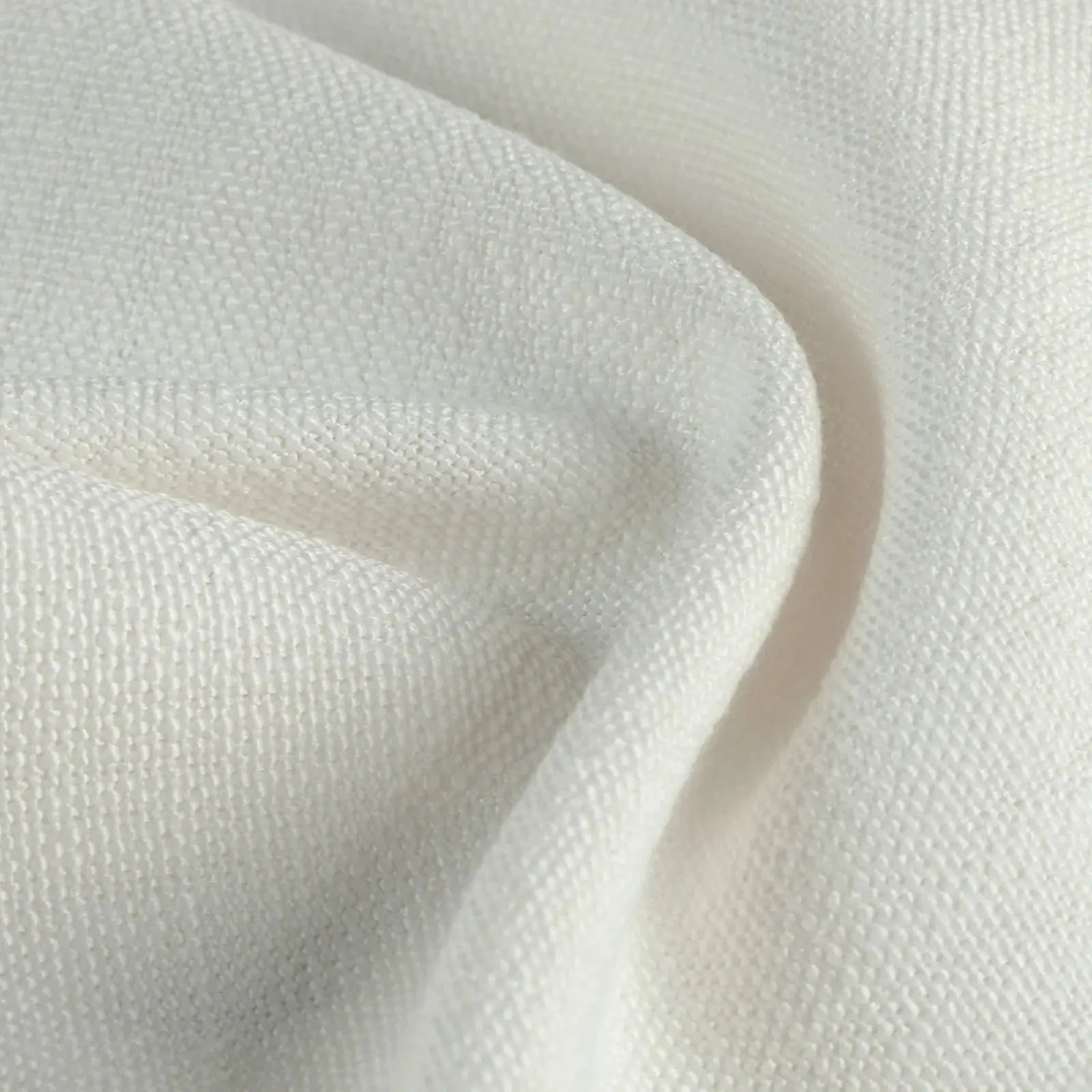 Close-up of cream white textured fabric draped in soft undulating folds
