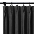 Dark charcoal linen-textured curtain with precise pleats hanging from a matte black rod and rings