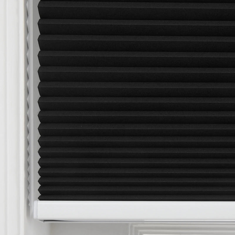 Close-up of a black cellular Blind featuring sharp horizontal pleats, neatly installed within a white window frame with a visible white bottom rail
