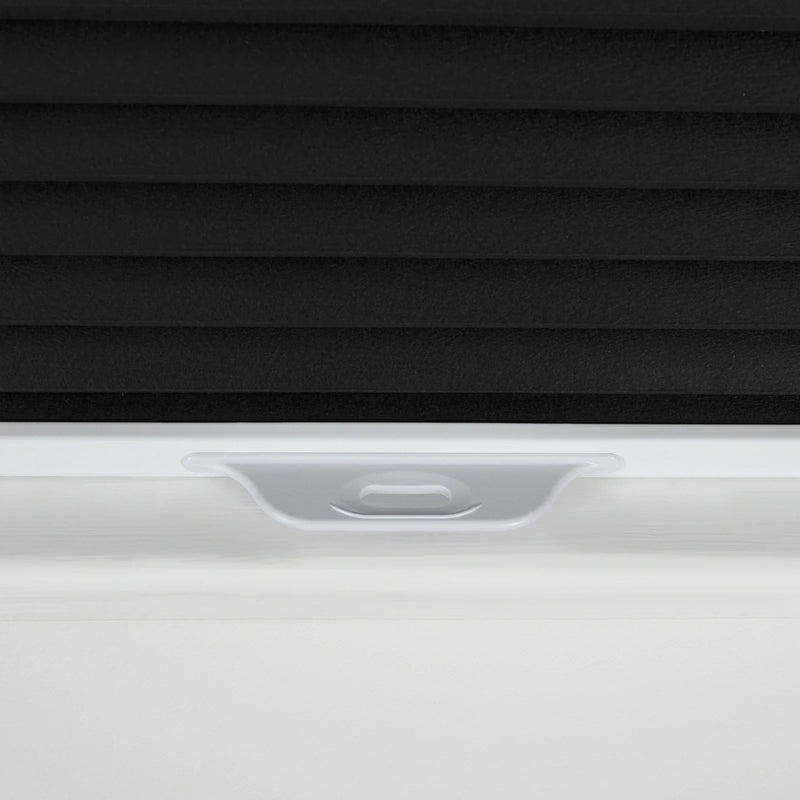 Product photography of a close-up detail of black textured cellular window Blinds partially lowered in a white window frame with a white plastic pull tab handle