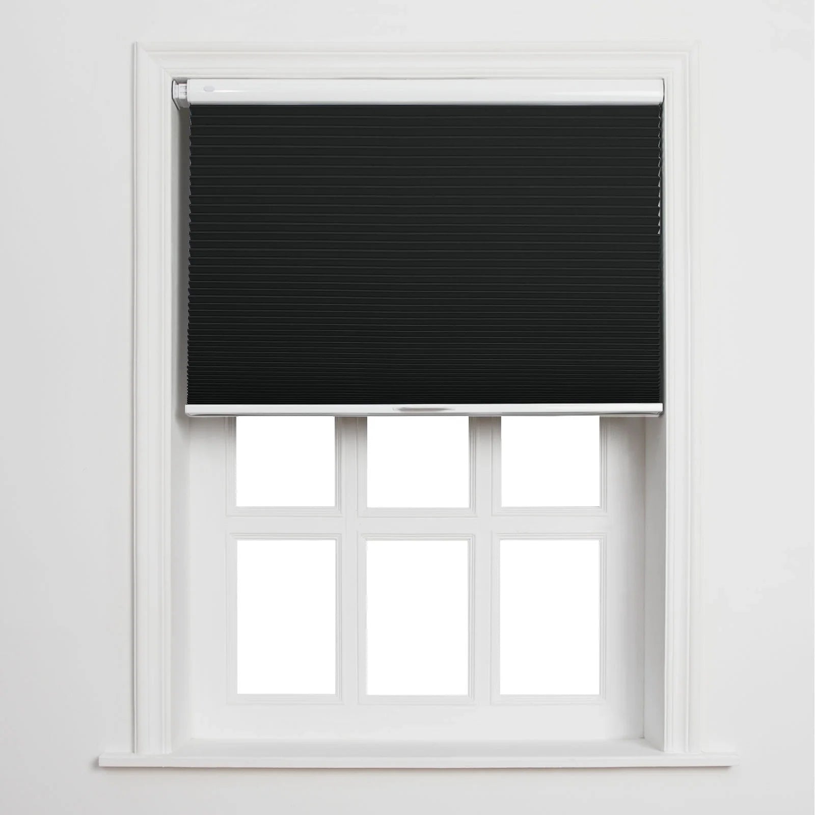 Black pleated cellular Blinds partially drawn on a white multi-pane window frame against a plain white wall