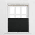 A white multi-pane window in a room featuring a black pleated cellular Blind positioned bottom-up covering the lower portion with white operational cords visible