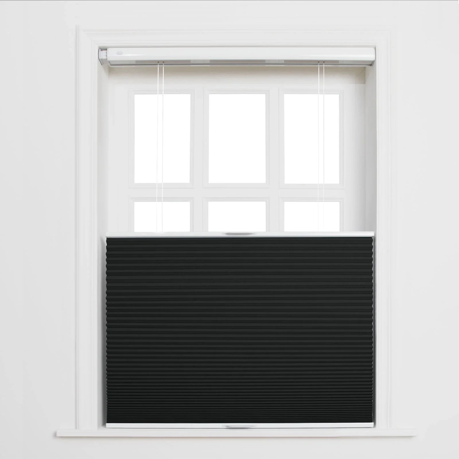 A white multi-pane window in a room featuring a black pleated cellular Blind positioned bottom-up covering the lower portion with white operational cords visible