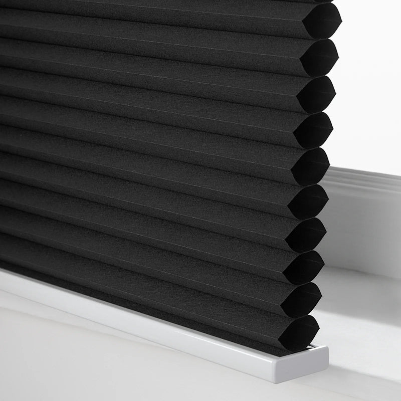 Photograph of black cellular Blinds with a textured honeycomb fabric and a crisp white bottom rail on a window