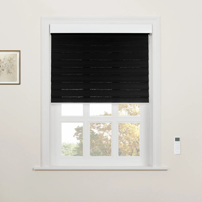 A window with a black layered zebra Blind partially covering a white multi-pane frame, revealing blurred autumn trees outside, with a white remote control on the right wall and a framed botanical print on the left