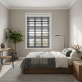 Modern bedroom interior featuring a wooden bed with cozy grey and white bedding, a large Fiddle Leaf Fig plant, and distinctive black and sheer zebra Blinds on the window