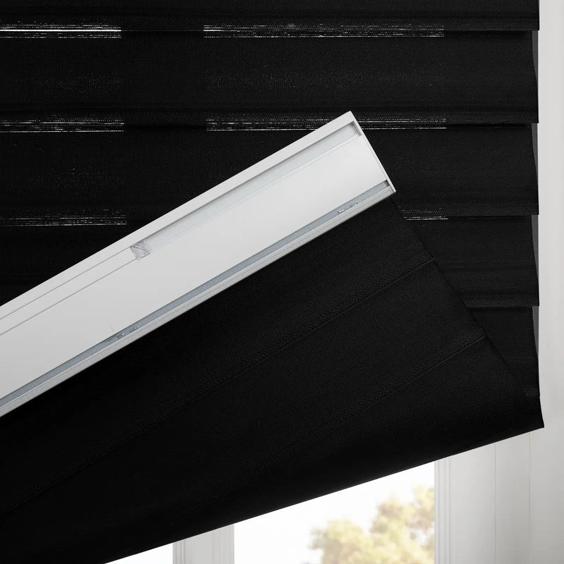 Black fabric zebra window Blinds with textured horizontal stripes partially lowered, showing the white headrail and a soft outdoor light from below