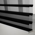 Close-up of modern zebra roller Blinds with alternating black opaque and sheer mesh horizontal stripes resting on a white bottom rail