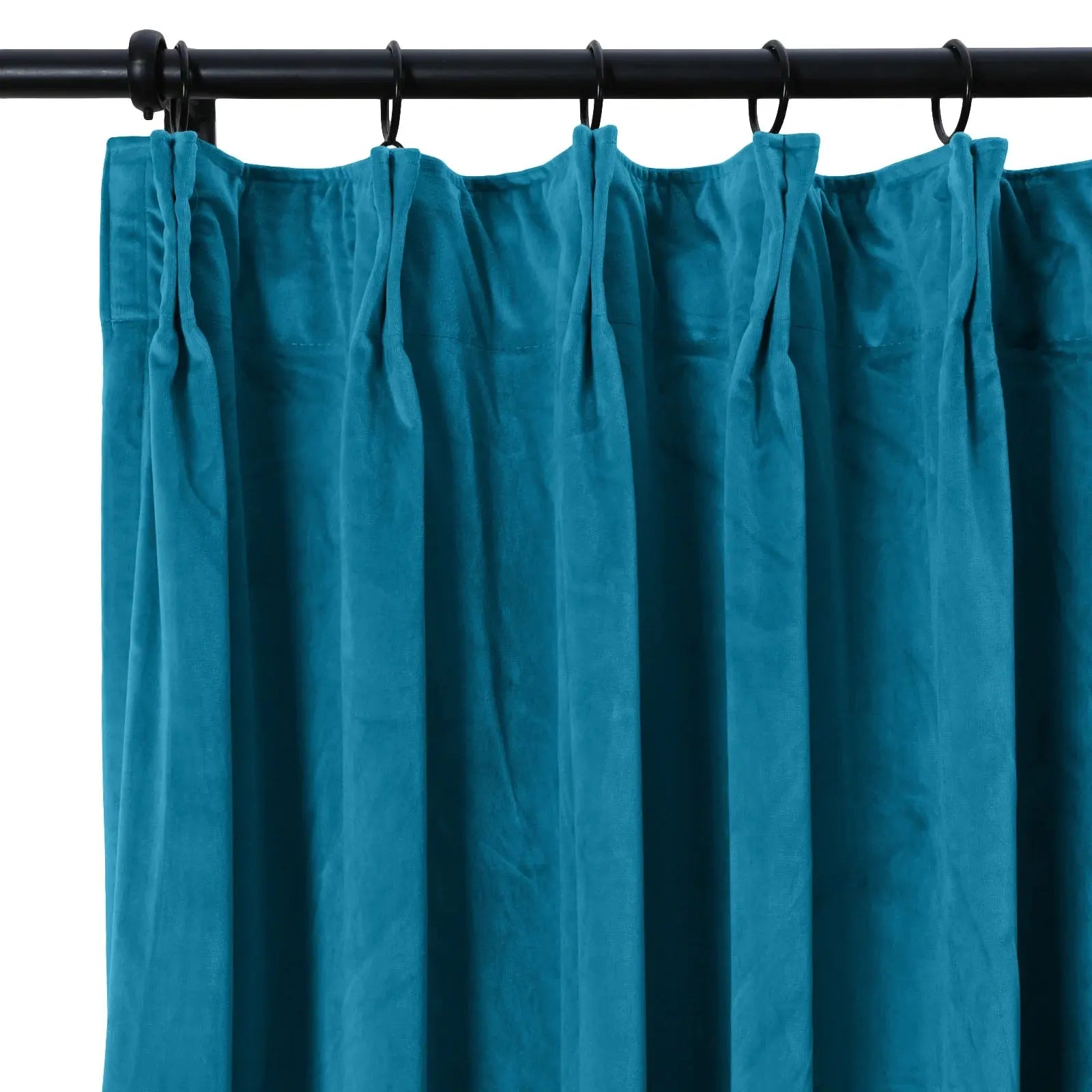 Teal velvet pleated curtain hanging on a black curtain rod with rings