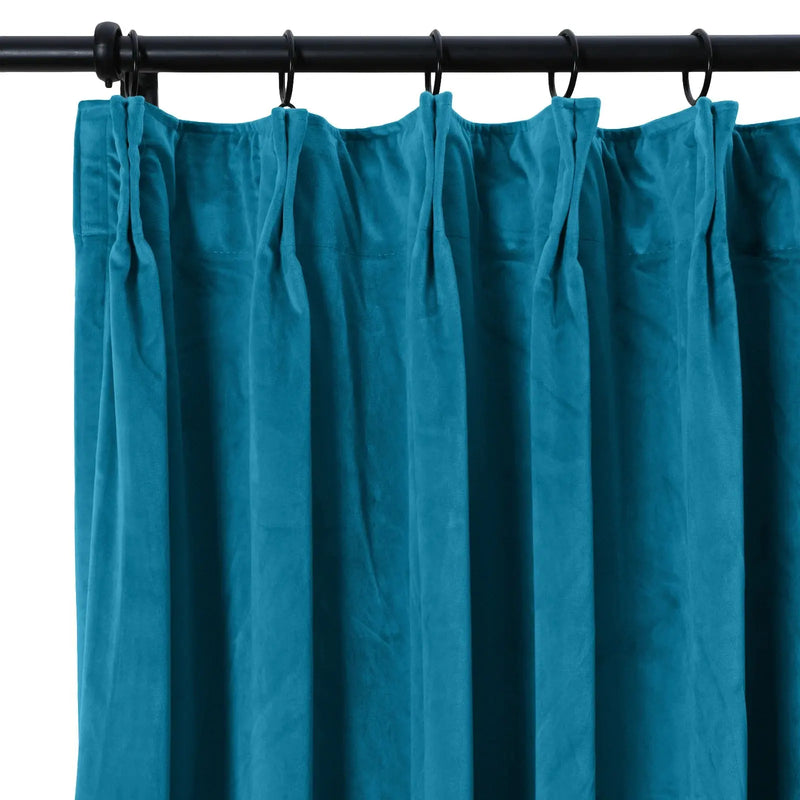 Teal velvet pleated curtain hanging on a black curtain rod with rings