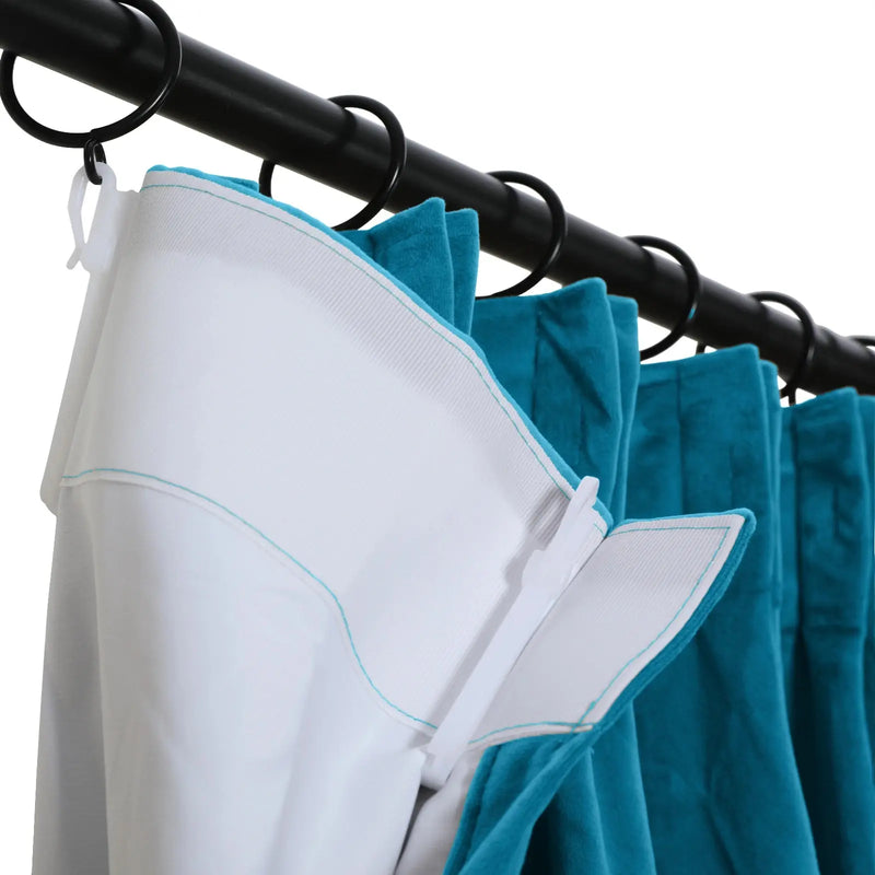 Close-up of a black curtain rod and rings holding a teal velvet curtain with a white pleated liner and light blue stitching