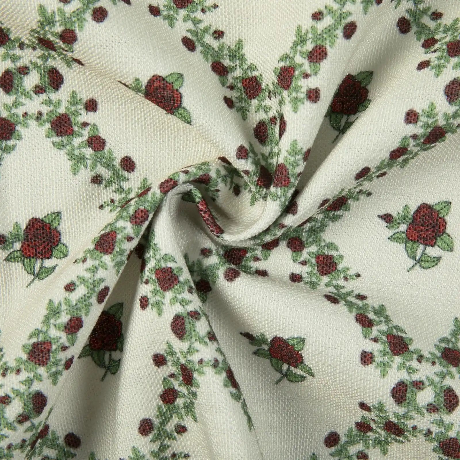 Woven fabric featuring a repeating pattern of dark red roses and green leaves on a cream background with a subtle textured weave and soft fabric folds