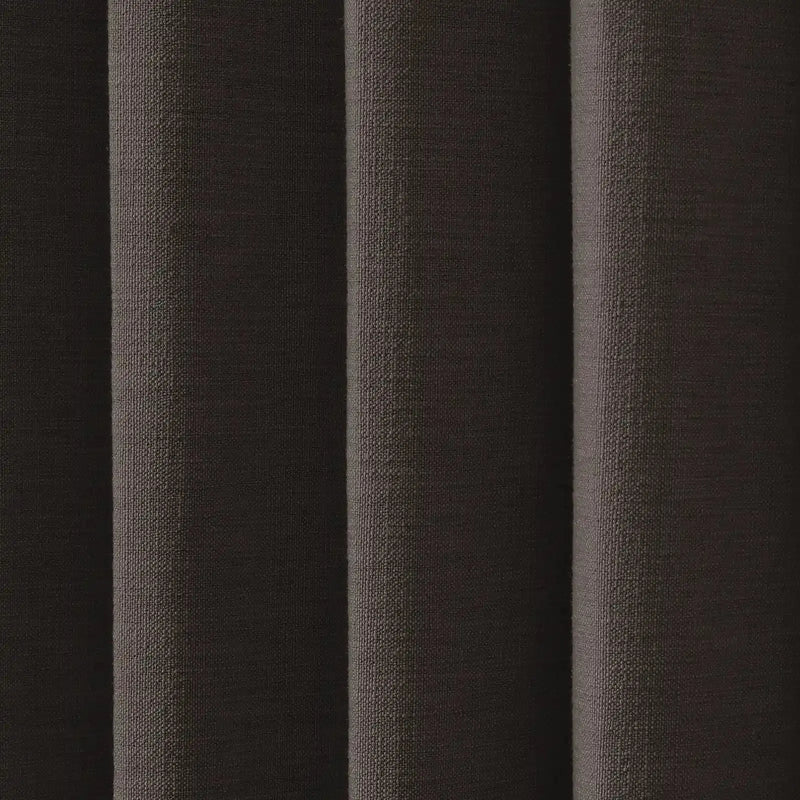 Photograph of dark brown textured fabric showing distinct vertical pleats a coarse woven pattern and subtle highlights on its nubbly surface