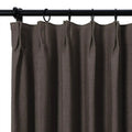 Dark brown pinch-pleat curtain with a visible woven texture hanging on a black metal rod with rings