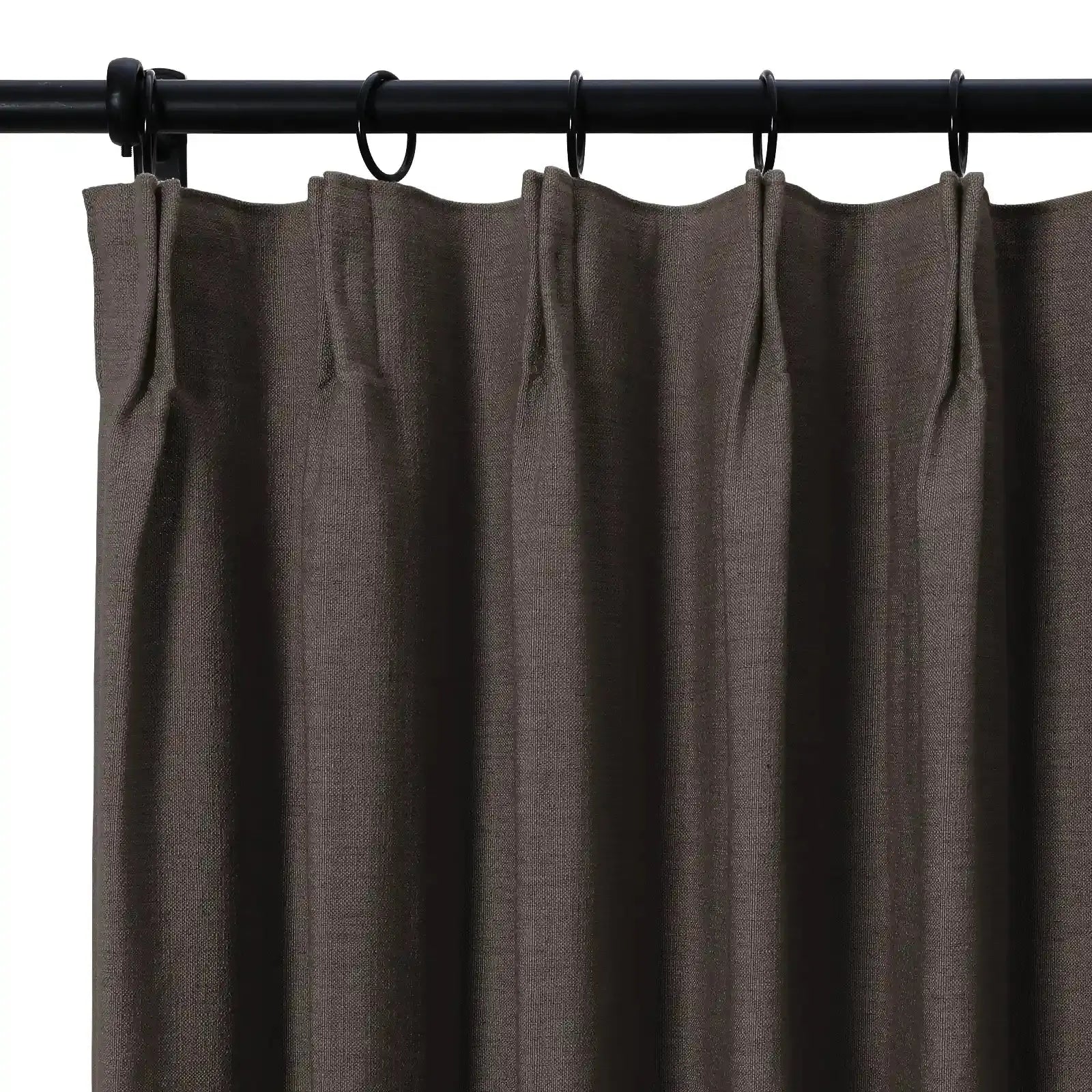 Dark brown pinch-pleat curtain with a visible woven texture hanging on a black metal rod with rings