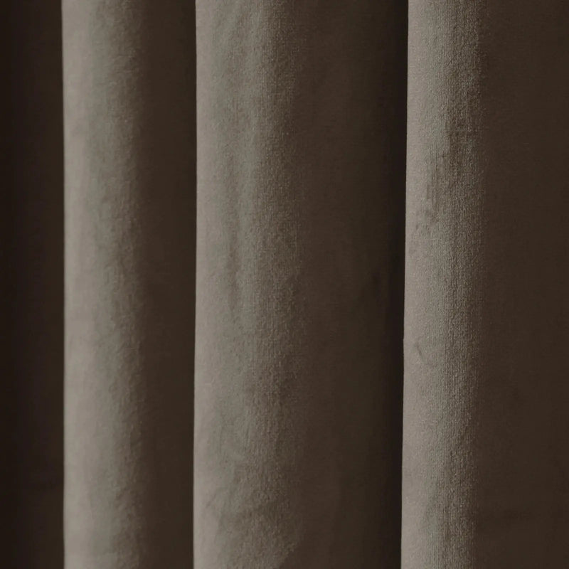 Close-up of pleated taupe velvet fabric showcasing its soft texture and dynamic light and shadow across vertical folds
