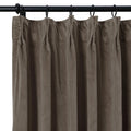Close-up of a taupe velvet pleated curtain hanging from black rings on a black rod