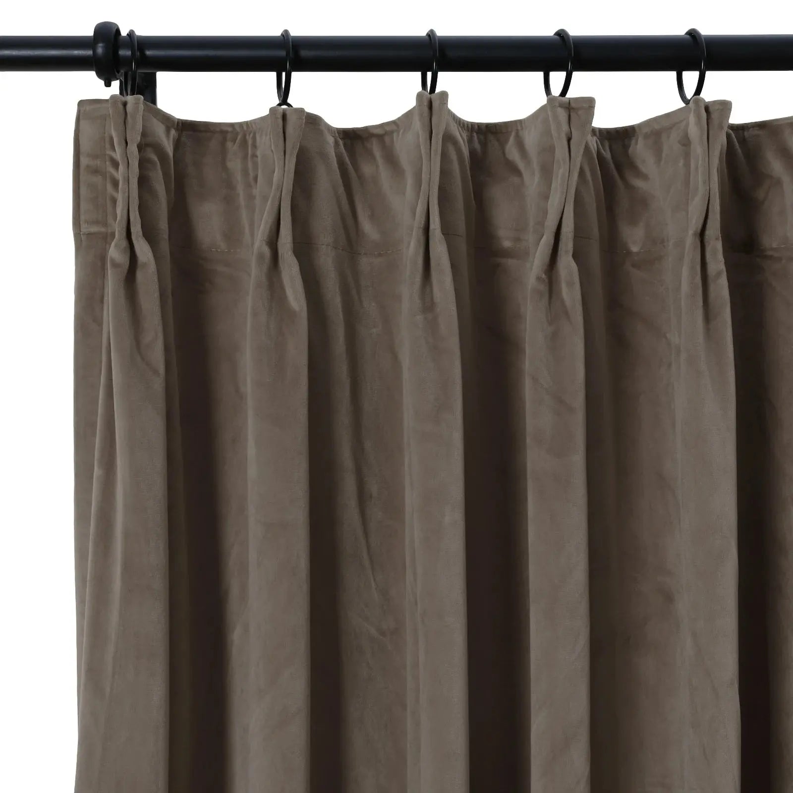 Close-up of a taupe velvet pleated curtain hanging from black rings on a black rod