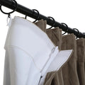 Close-up of a brown pleated velvet curtain with white pleating tape and plastic hooks attached to black rings on a black curtain rod