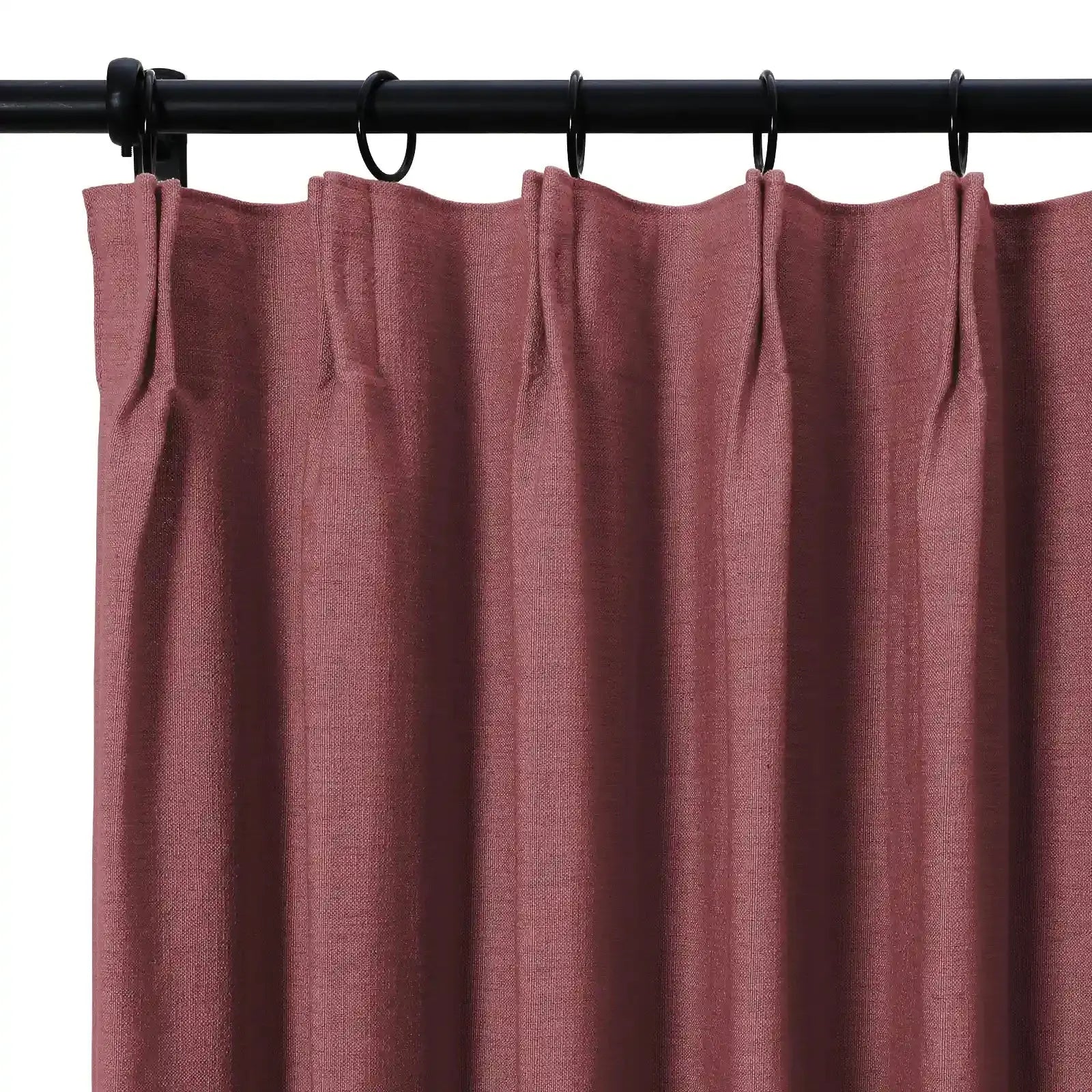 Textured dusty rose curtain panel with tailored pleats on a black rod and rings