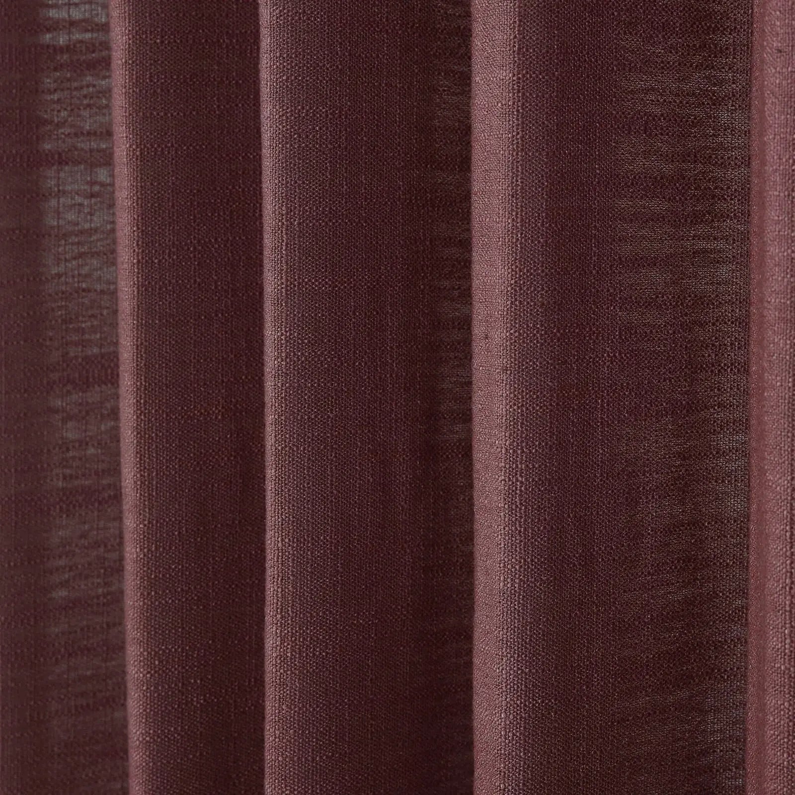 Close-up of a maroon textured curtain featuring distinct vertical folds and a visible coarse weave