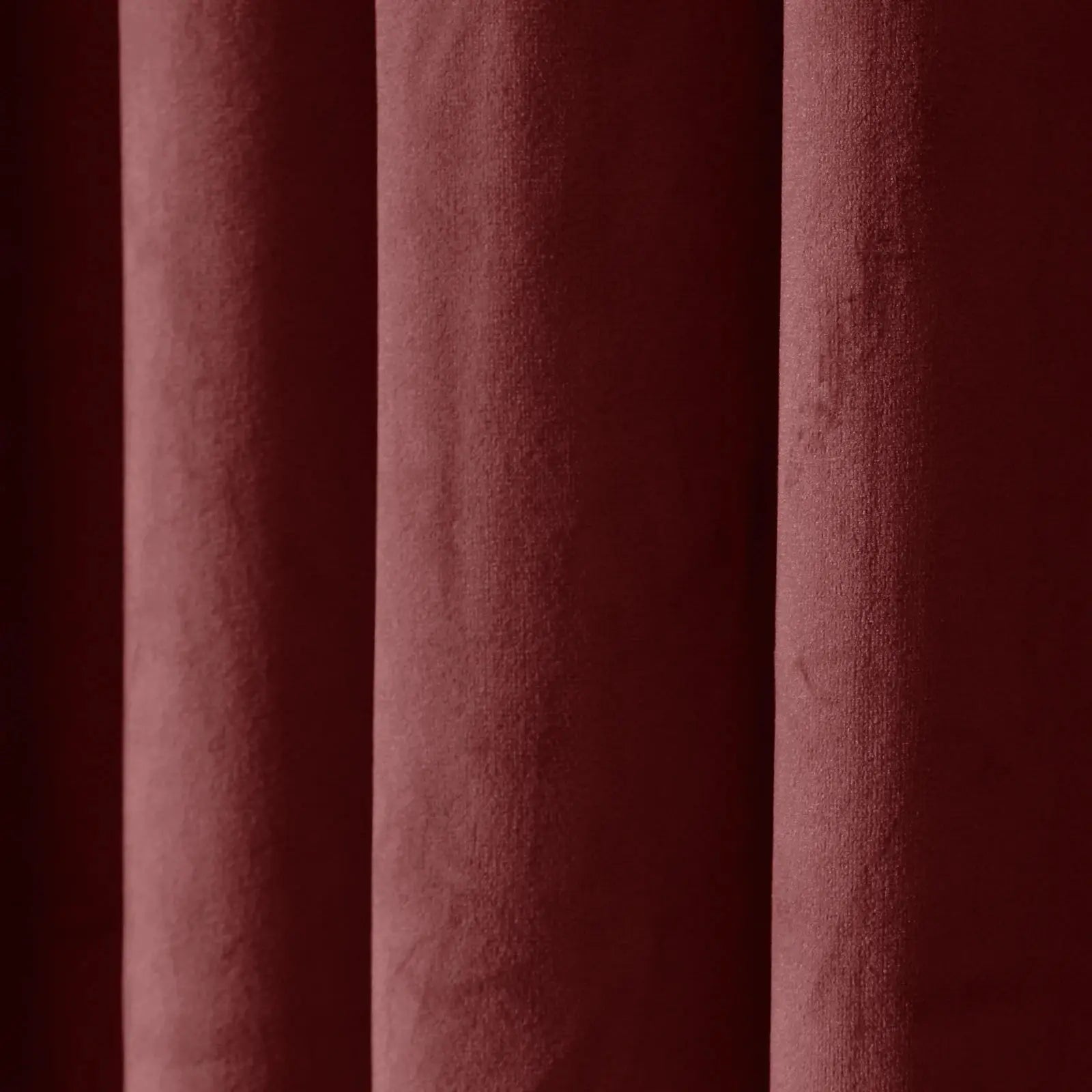 Deep burgundy velvet fabric showcasing its plush texture and soft vertical folds with subtle light and shadow play