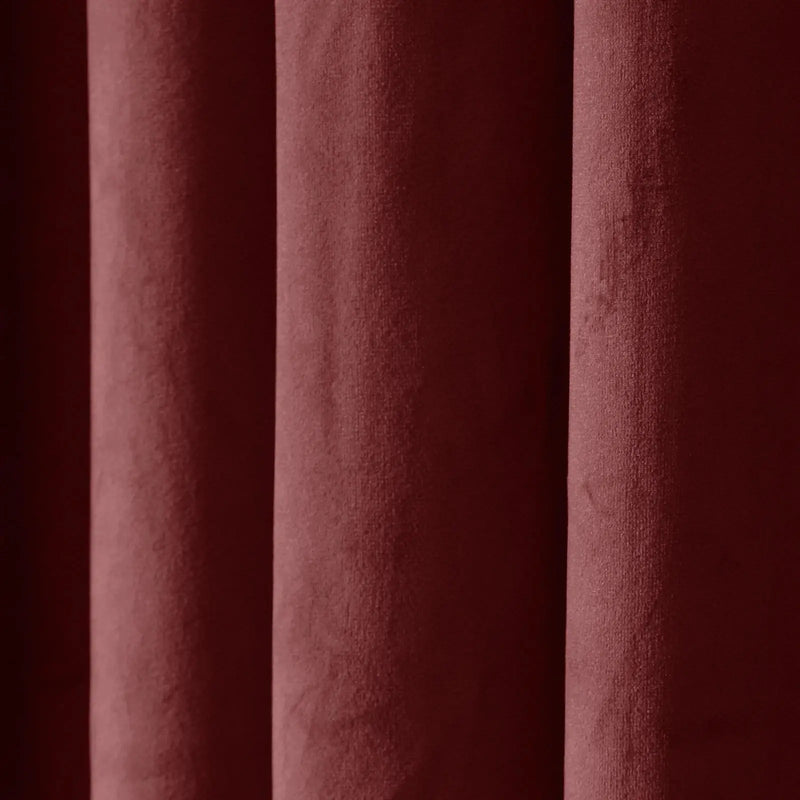 Deep burgundy velvet fabric showcasing its plush texture and soft vertical folds with subtle light and shadow play