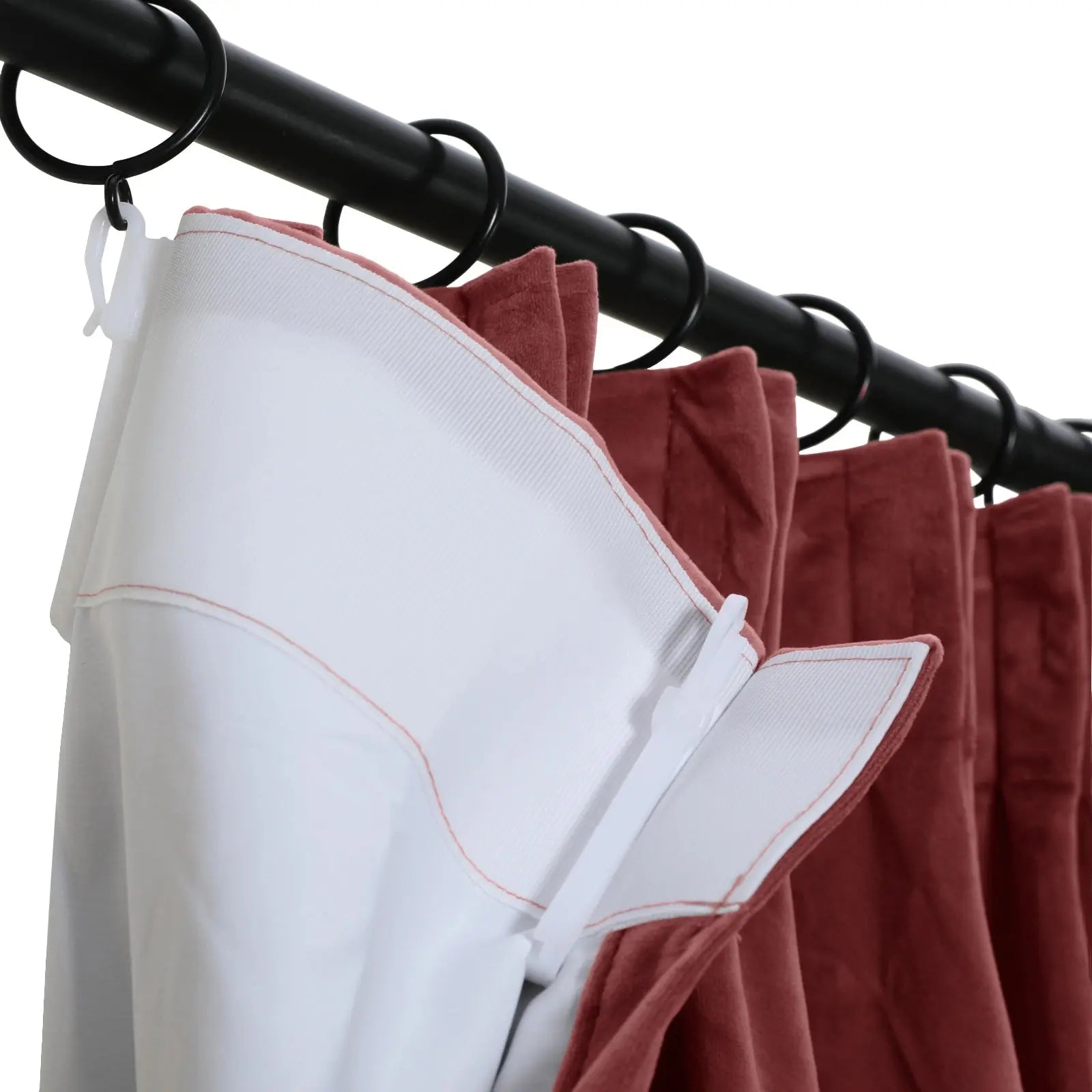 Photograph of terracotta velvet curtains with white backing hanging from a black curtain rod using black rings and white plastic hooks