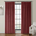 Deep red velvet pleated curtains on a black rod frame a large window with black grid panes in a room also showing a modern gray tree artwork and a neutral armchair with a white textured throw