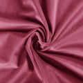 A close-up of plush deep rose pink velvet fabric artfully swirled creating a central rosette pattern and soft light-catching folds