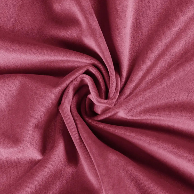 A close-up of plush deep rose pink velvet fabric artfully swirled creating a central rosette pattern and soft light-catching folds