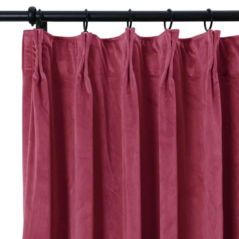 Deep magenta velvet pinch pleat curtain hanging from a black metal rod with rings